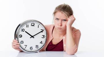 complaining beautiful young blond woman holding a clock